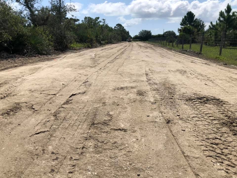 Wide graded dirt road cut through brush and pines