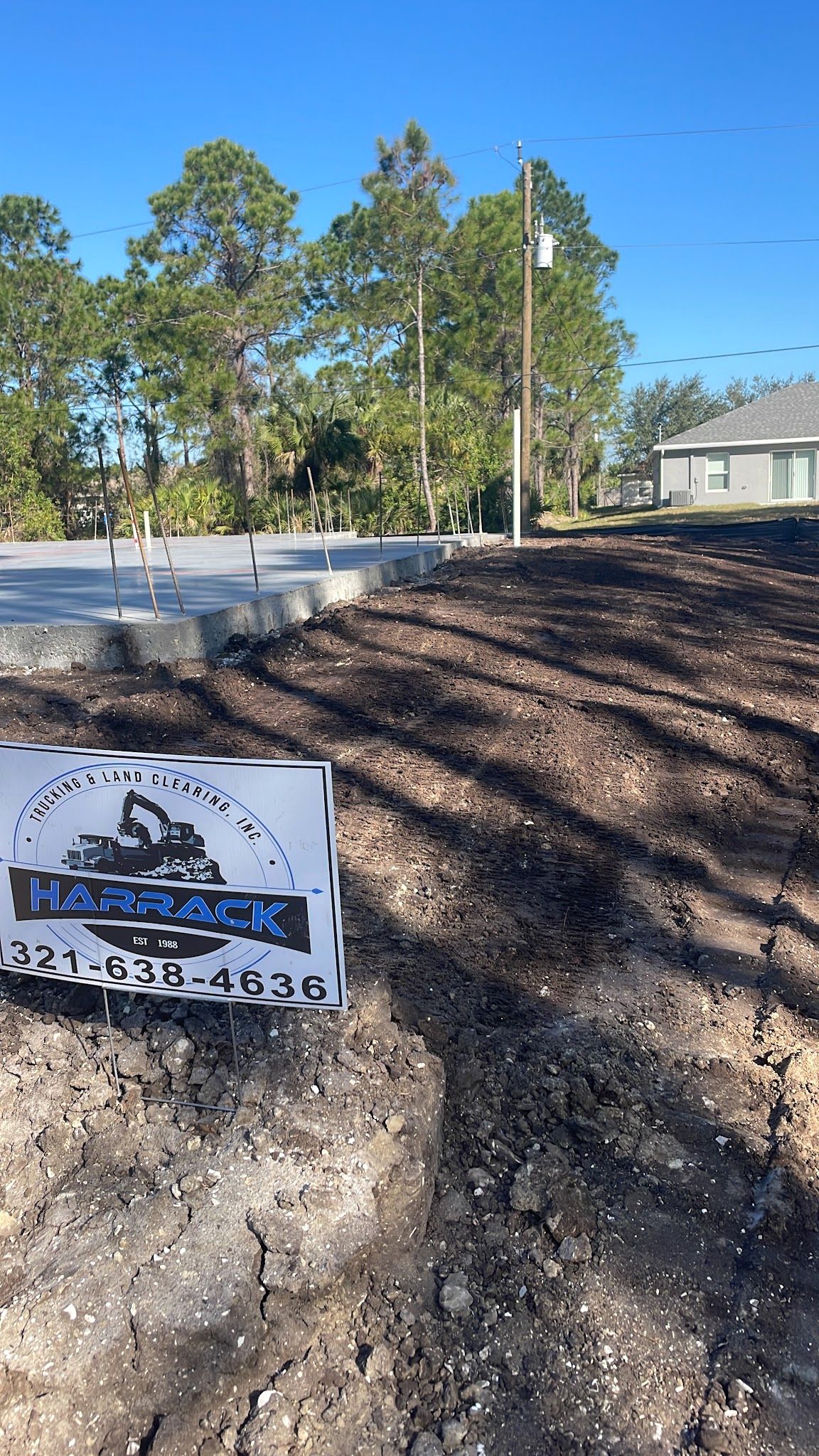 Finished dirt building pad by a street with a Harrack yard sign